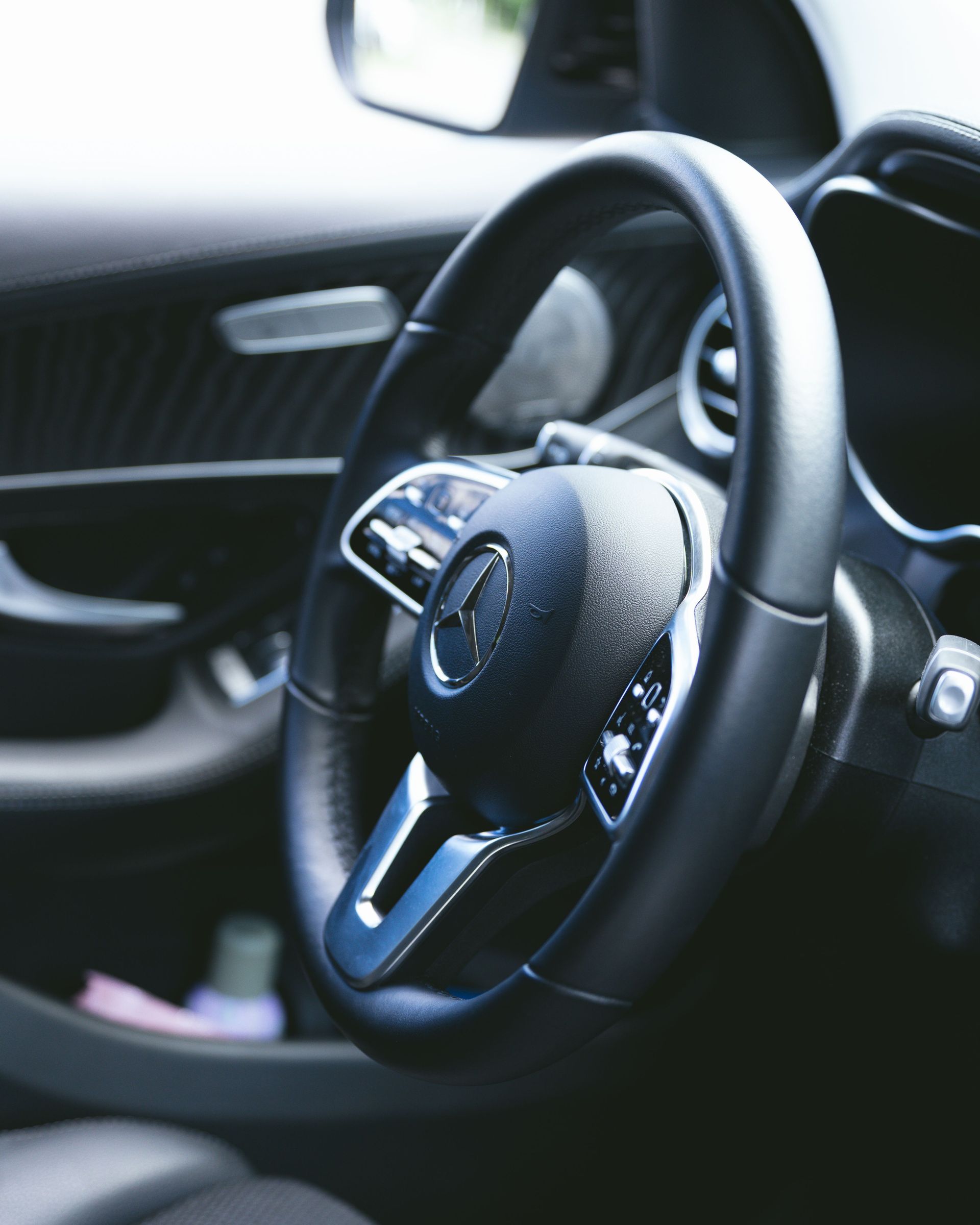 Close-up of a luxury car's sleek steering wheel showcasing design and craftsmanship.