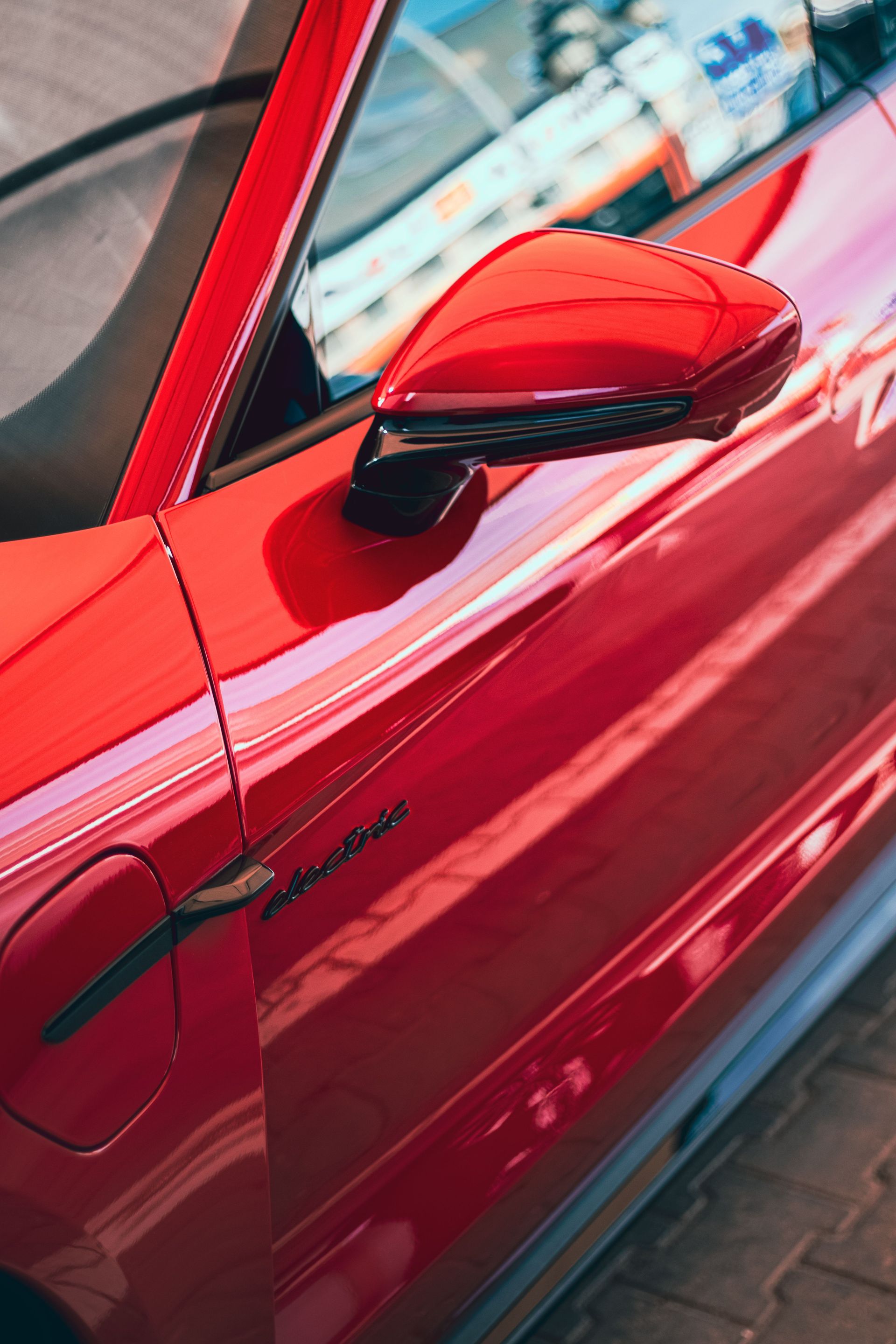 A vibrant red sports car door with sleek lines and a shiny mirror, capturing modern automotive design.