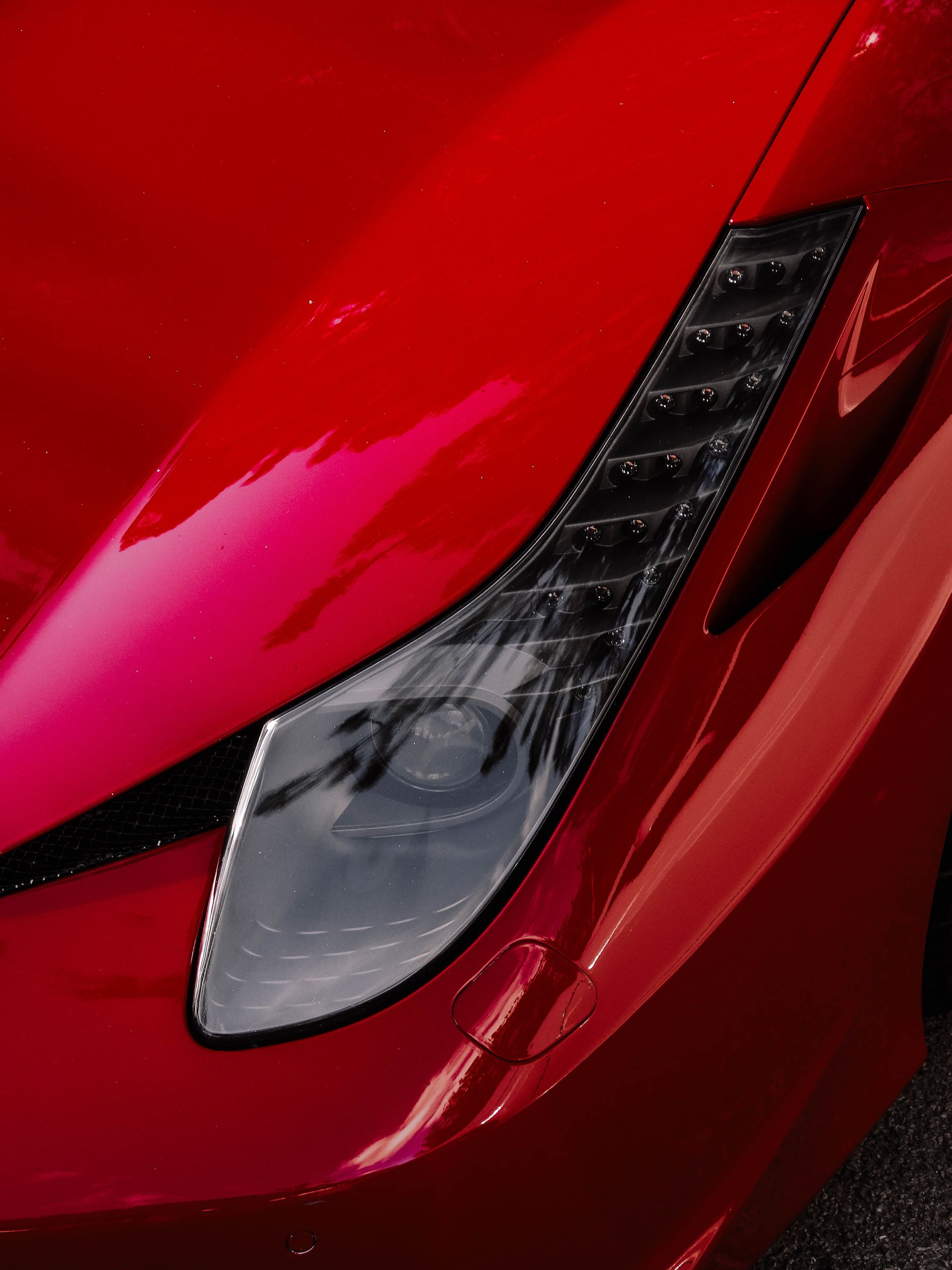 Detailed capture of a Ferrari's sleek red exterior and headlight in Ankara.